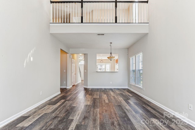 interior space with a towering ceiling and dark hardwood / wood-style flooring