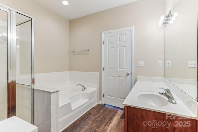 bathroom featuring vanity, a bath, and wood-type flooring