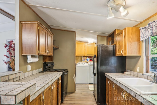 kitchen with washing machine and clothes dryer, tile counters, sink, and black appliances