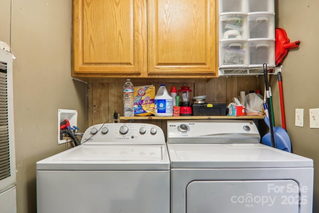 clothes washing area with cabinets and washing machine and clothes dryer