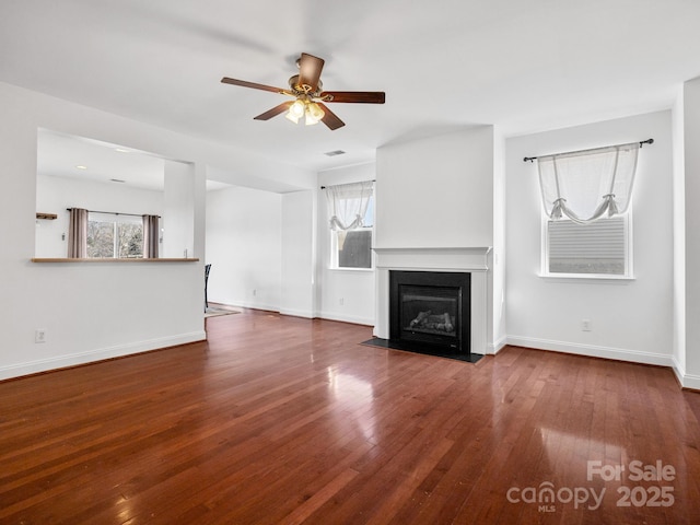 unfurnished living room featuring dark wood-type flooring and ceiling fan