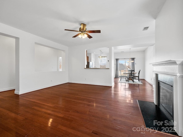 unfurnished living room with a high end fireplace, dark hardwood / wood-style floors, and ceiling fan with notable chandelier