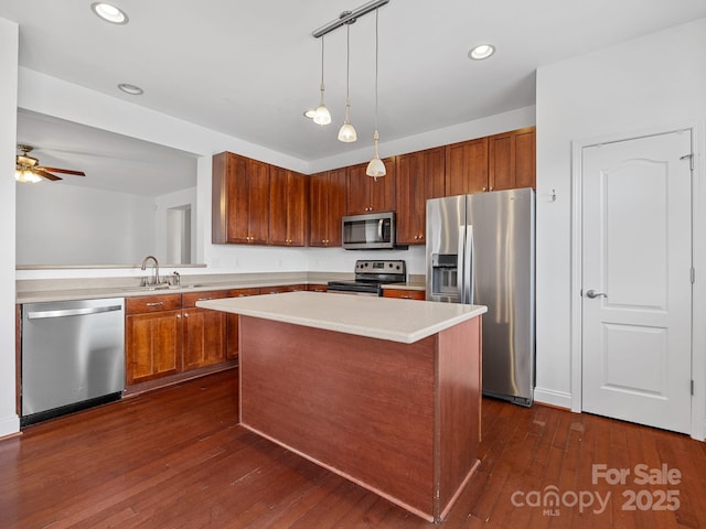 kitchen with appliances with stainless steel finishes, a center island, sink, and dark hardwood / wood-style flooring