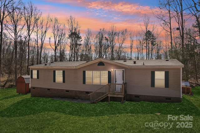 manufactured / mobile home with crawl space, a shed, an outdoor structure, and a front yard