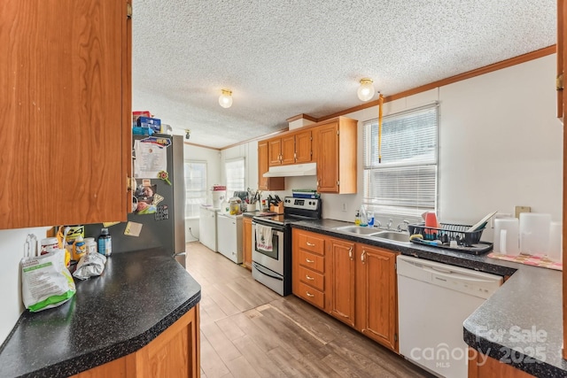 kitchen featuring white dishwasher, a sink, washer and dryer, dark countertops, and stainless steel range with electric stovetop