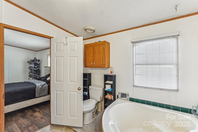 ensuite bathroom with crown molding, toilet, connected bathroom, a textured ceiling, and a bath