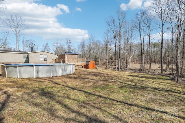 view of yard with a storage unit, an outdoor pool, and an outbuilding