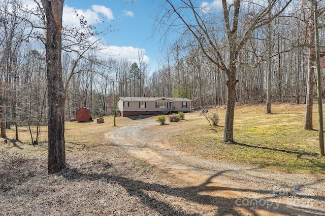 manufactured / mobile home with an outbuilding, dirt driveway, a storage shed, crawl space, and a front lawn