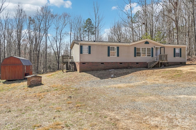 view of front facade featuring crawl space, a shed, stairway, and an outbuilding