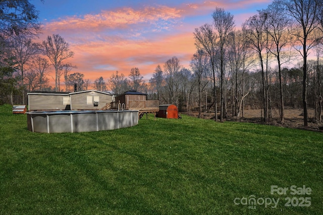 yard at dusk featuring an outdoor pool