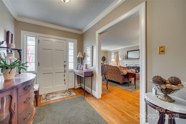 foyer entrance with ornamental molding, a textured ceiling, and light hardwood / wood-style flooring