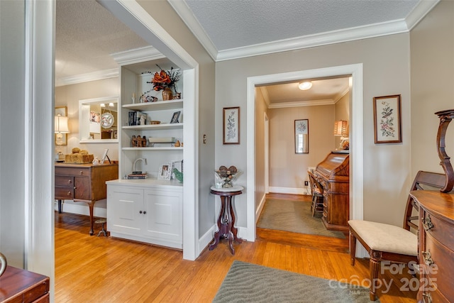 hall featuring ornamental molding, light hardwood / wood-style floors, and a textured ceiling