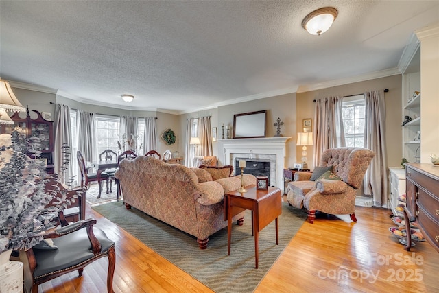 living room featuring crown molding, a healthy amount of sunlight, a fireplace, and wood-type flooring