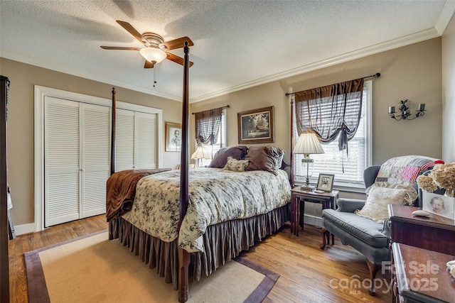 bedroom with ornamental molding, ceiling fan, a textured ceiling, and light wood-type flooring