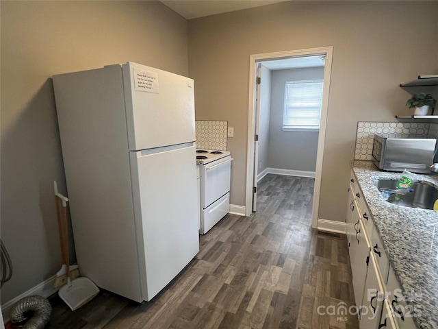 kitchen featuring sink, tasteful backsplash, white appliances, light stone countertops, and white cabinets