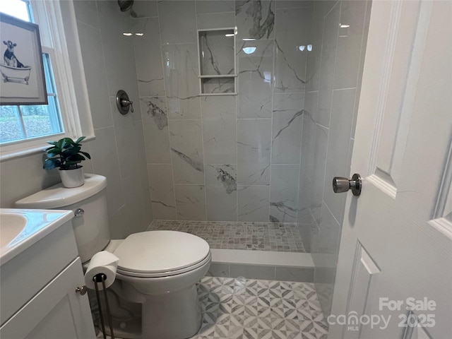 bathroom featuring vanity, tiled shower, and toilet