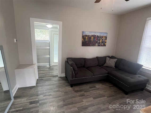 living room featuring ceiling fan, dark wood-type flooring, and a healthy amount of sunlight