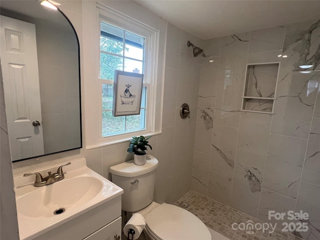 bathroom featuring a healthy amount of sunlight, vanity, and a tile shower