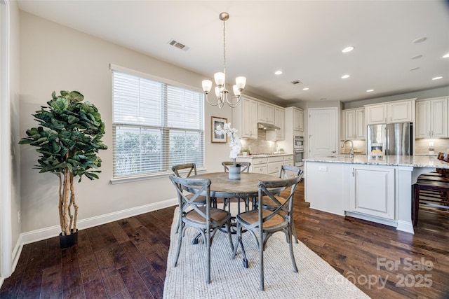 dining room featuring dark wood-type flooring, sink, and a chandelier