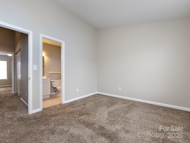 unfurnished bedroom with ensuite bath and carpet flooring