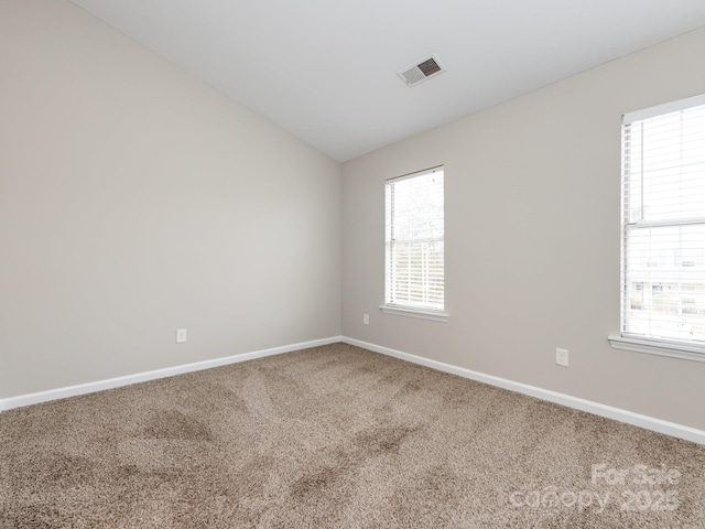 carpeted empty room featuring vaulted ceiling and plenty of natural light