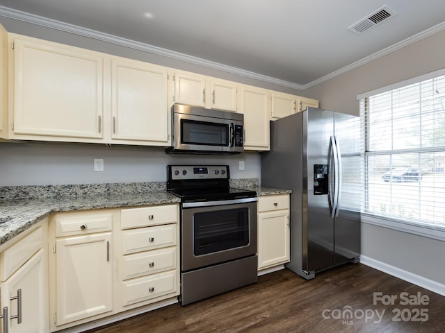 kitchen with light stone counters, plenty of natural light, ornamental molding, and appliances with stainless steel finishes