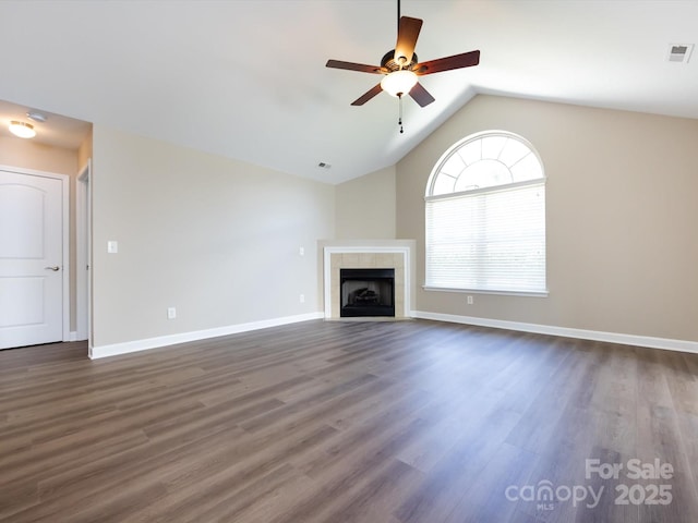 unfurnished living room with dark hardwood / wood-style flooring, a tiled fireplace, lofted ceiling, and ceiling fan