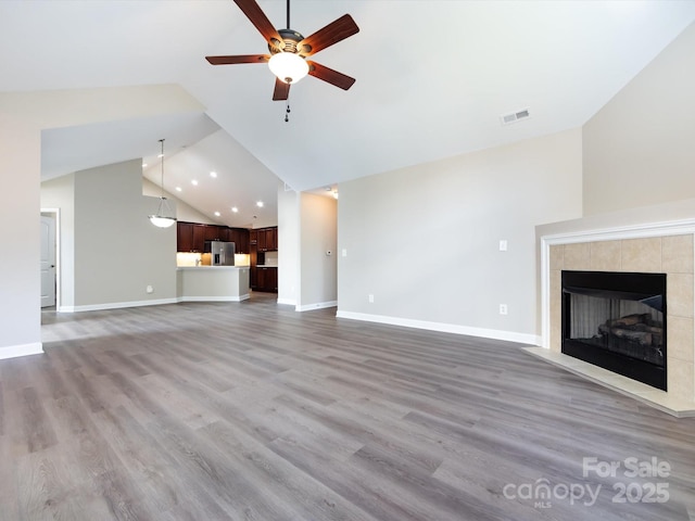 unfurnished living room featuring light hardwood / wood-style flooring, a fireplace, high vaulted ceiling, and ceiling fan