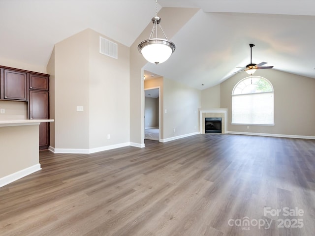 unfurnished living room with ceiling fan, lofted ceiling, hardwood / wood-style floors, and a fireplace