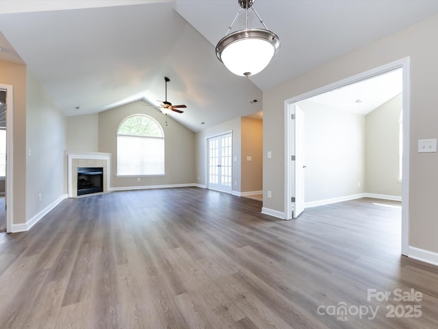 unfurnished living room with a tiled fireplace, hardwood / wood-style flooring, lofted ceiling, and ceiling fan