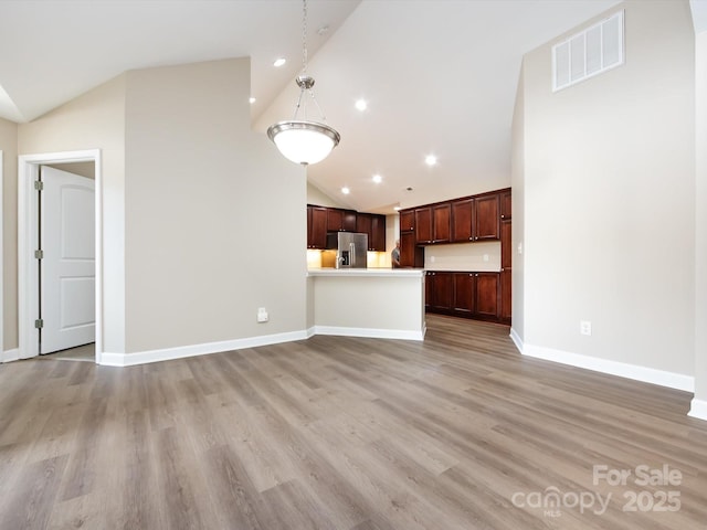 unfurnished living room with high vaulted ceiling and light wood-type flooring