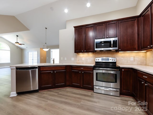 kitchen featuring lofted ceiling, sink, hanging light fixtures, light hardwood / wood-style flooring, and stainless steel appliances