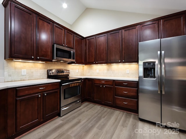 kitchen featuring tasteful backsplash, light hardwood / wood-style flooring, stainless steel appliances, and vaulted ceiling