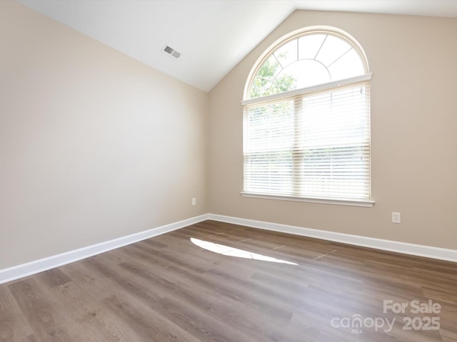 spare room with vaulted ceiling and hardwood / wood-style floors