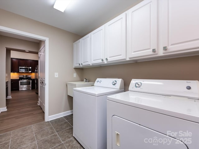 clothes washing area with cabinets, washer and dryer, sink, and dark tile patterned floors