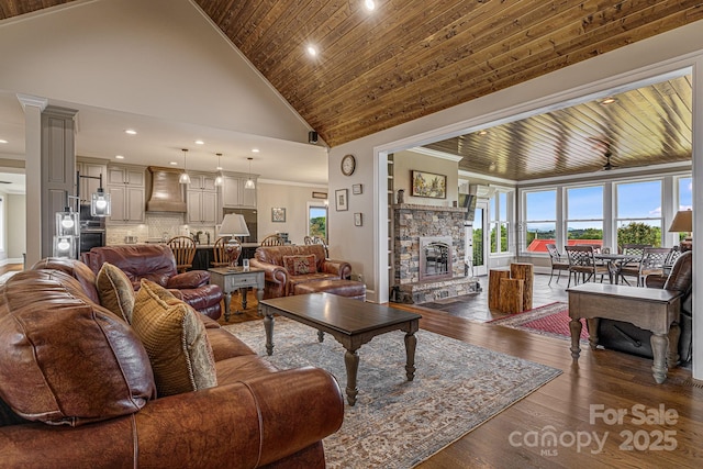 living room featuring dark wood-type flooring, a stone fireplace, crown molding, high vaulted ceiling, and wooden ceiling