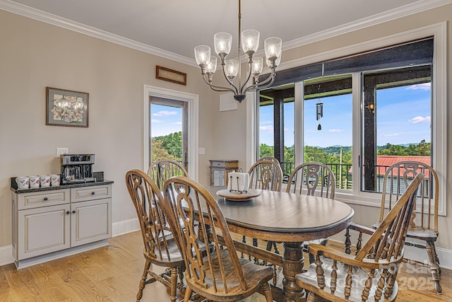 dining area with ornamental molding, an inviting chandelier, and light hardwood / wood-style floors