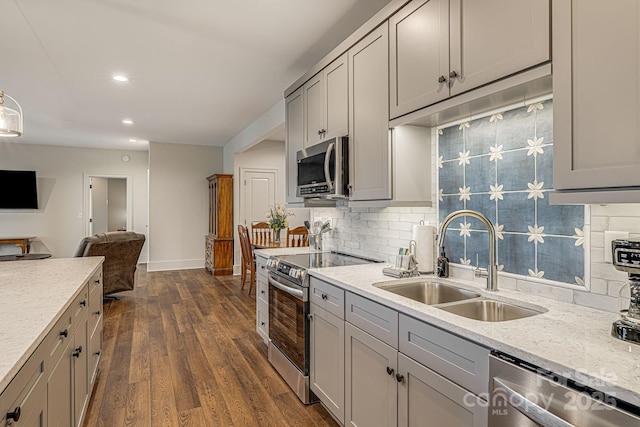 kitchen featuring appliances with stainless steel finishes, tasteful backsplash, sink, gray cabinetry, and dark hardwood / wood-style flooring