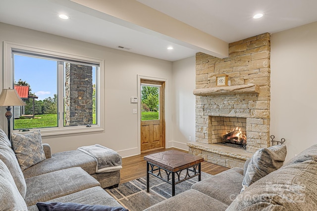 living room featuring beamed ceiling, a fireplace, and hardwood / wood-style floors