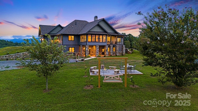 back house at dusk with a yard and a patio