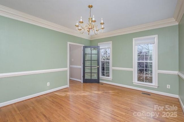 unfurnished room featuring hardwood / wood-style floors, a notable chandelier, and ornamental molding