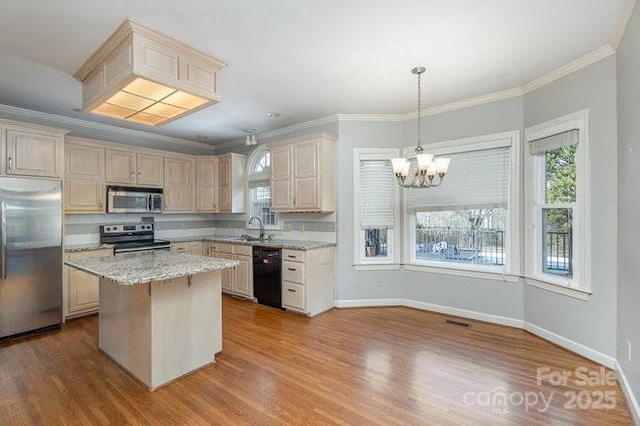 kitchen with pendant lighting, stainless steel appliances, a center island, light stone counters, and ornamental molding