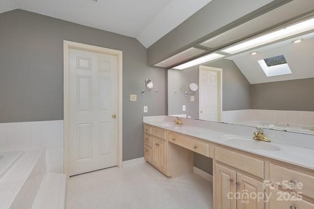 bathroom featuring vanity, tiled tub, and vaulted ceiling