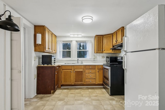 kitchen featuring white refrigerator, stainless steel electric stove, sink, and decorative backsplash