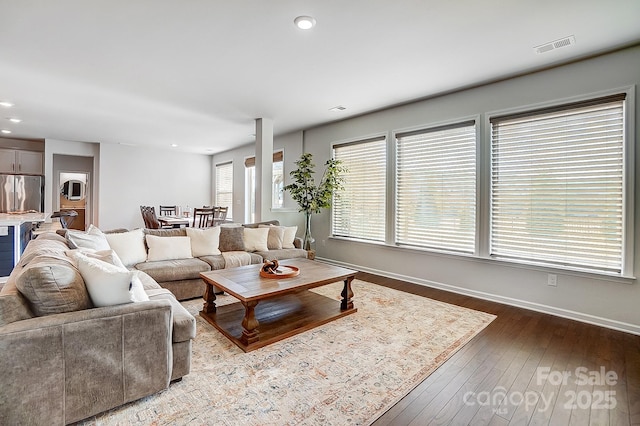 living room with visible vents, baseboards, wood finished floors, and recessed lighting