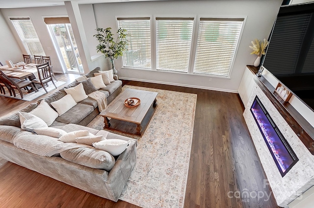 living room featuring baseboards, dark wood finished floors, and a glass covered fireplace