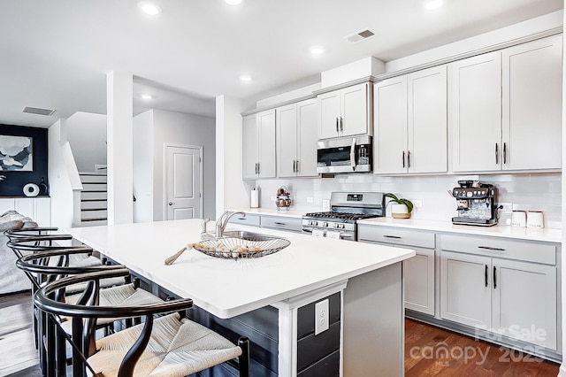 kitchen with a center island with sink, visible vents, stainless steel appliances, and light countertops