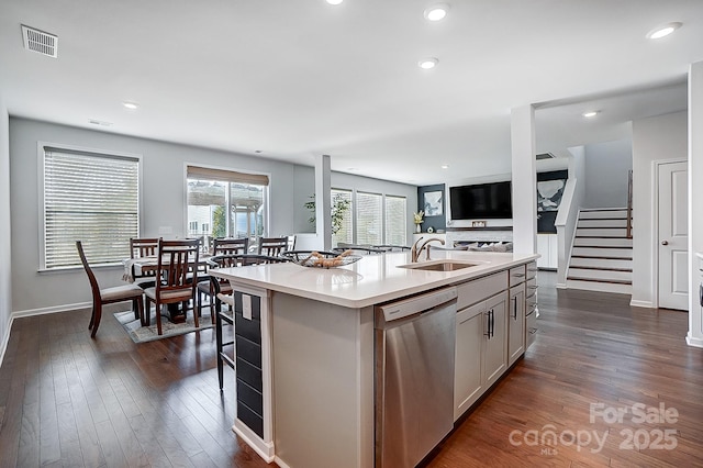 kitchen with a sink, open floor plan, light countertops, dishwasher, and an island with sink