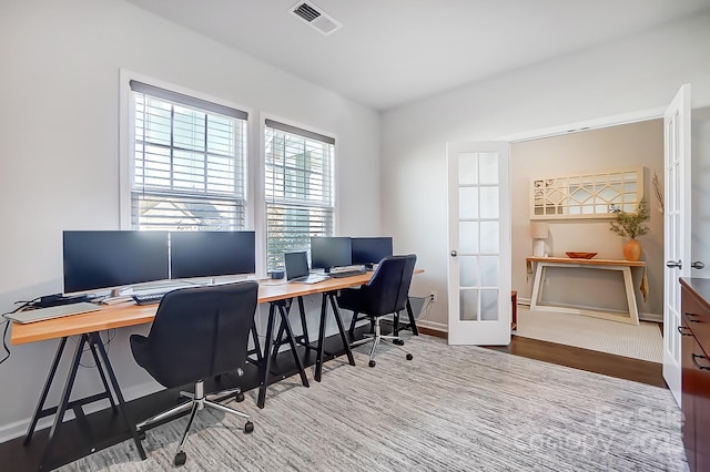 office with baseboards, visible vents, wood finished floors, and french doors