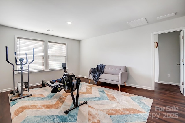 exercise area with visible vents, baseboards, and wood finished floors